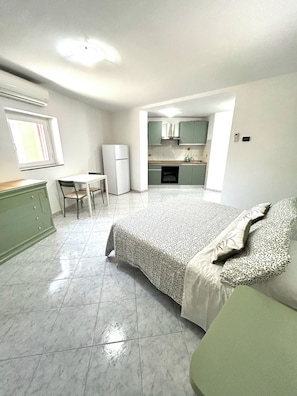 A compact bedroom with a bed, a small desk, and a kitchenette in the background. - Verde Salvia Home - Vacation Rental in Frascati (Frascati)