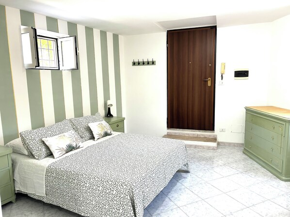 A bedroom with a bed, nightstand, dresser, and a wooden door. - Verde Salvia Home - Vacation Rental in Frascati (Frascati)