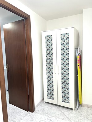 A room with a wooden door, a white wardrobe with patterned doors, and a yellow cleaning tool. - Verde Salvia Home - Vacation Rental in Frascati (Frascati)