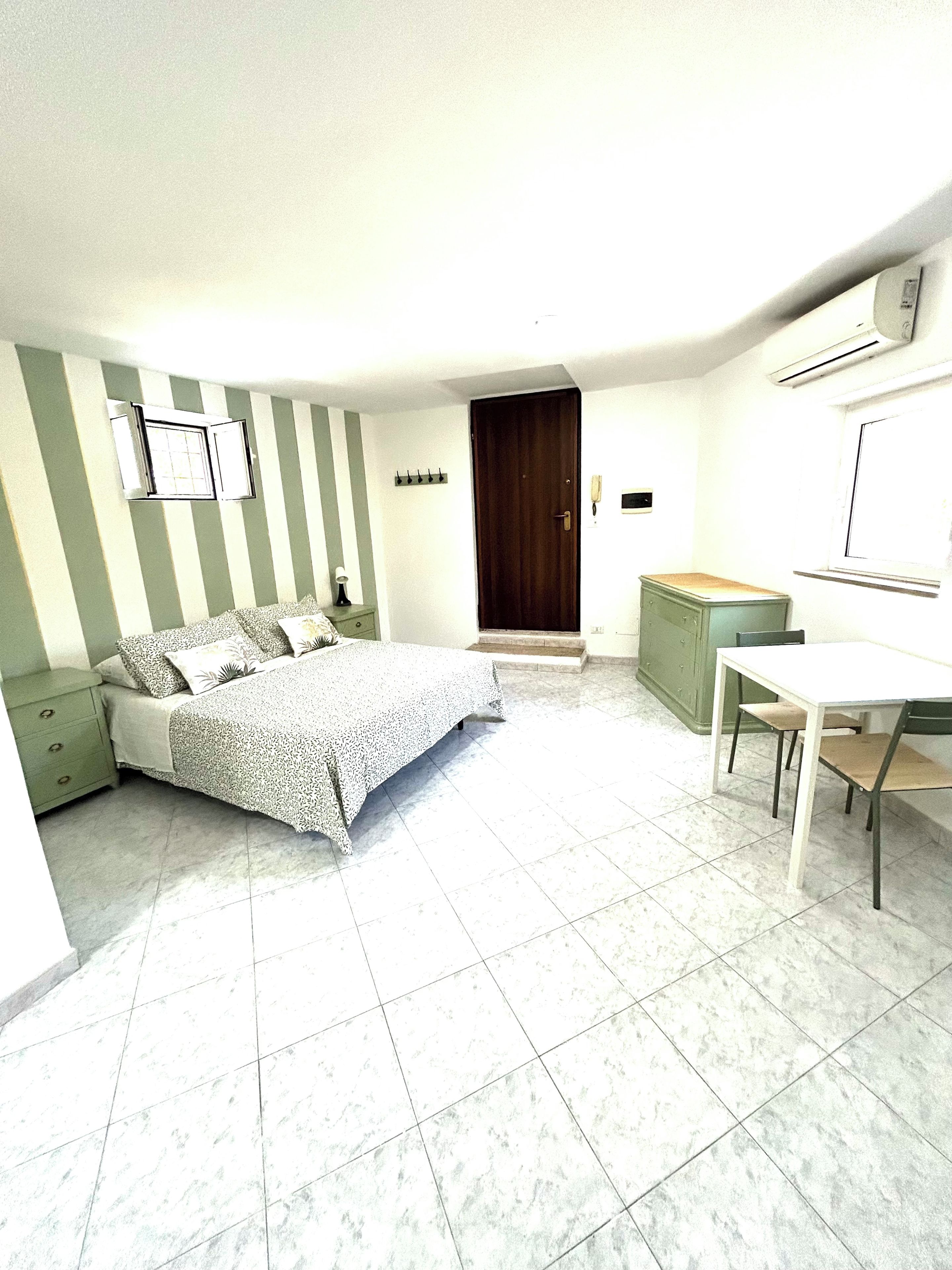 A bedroom with a bed, a desk, and a wardrobe.