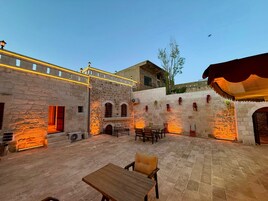 Un patio al aire libre con paredes de piedra, una mesa de madera y sillas.