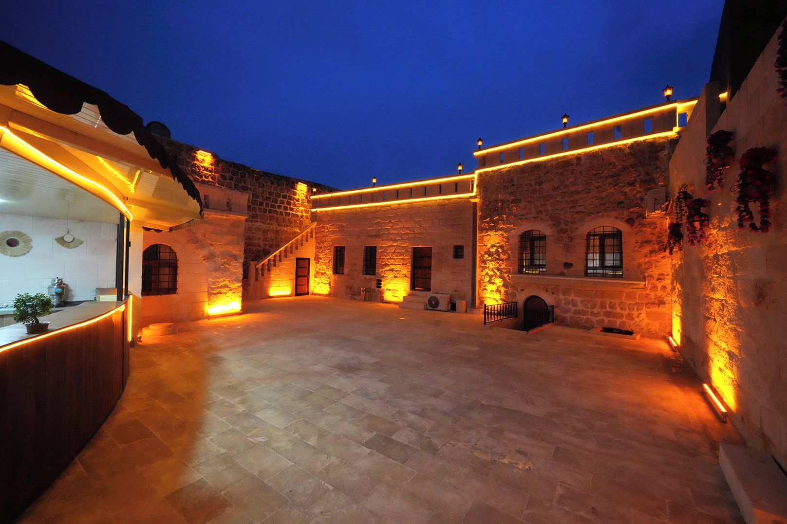 A courtyard with stone walls, a wooden bench, and a staircase.