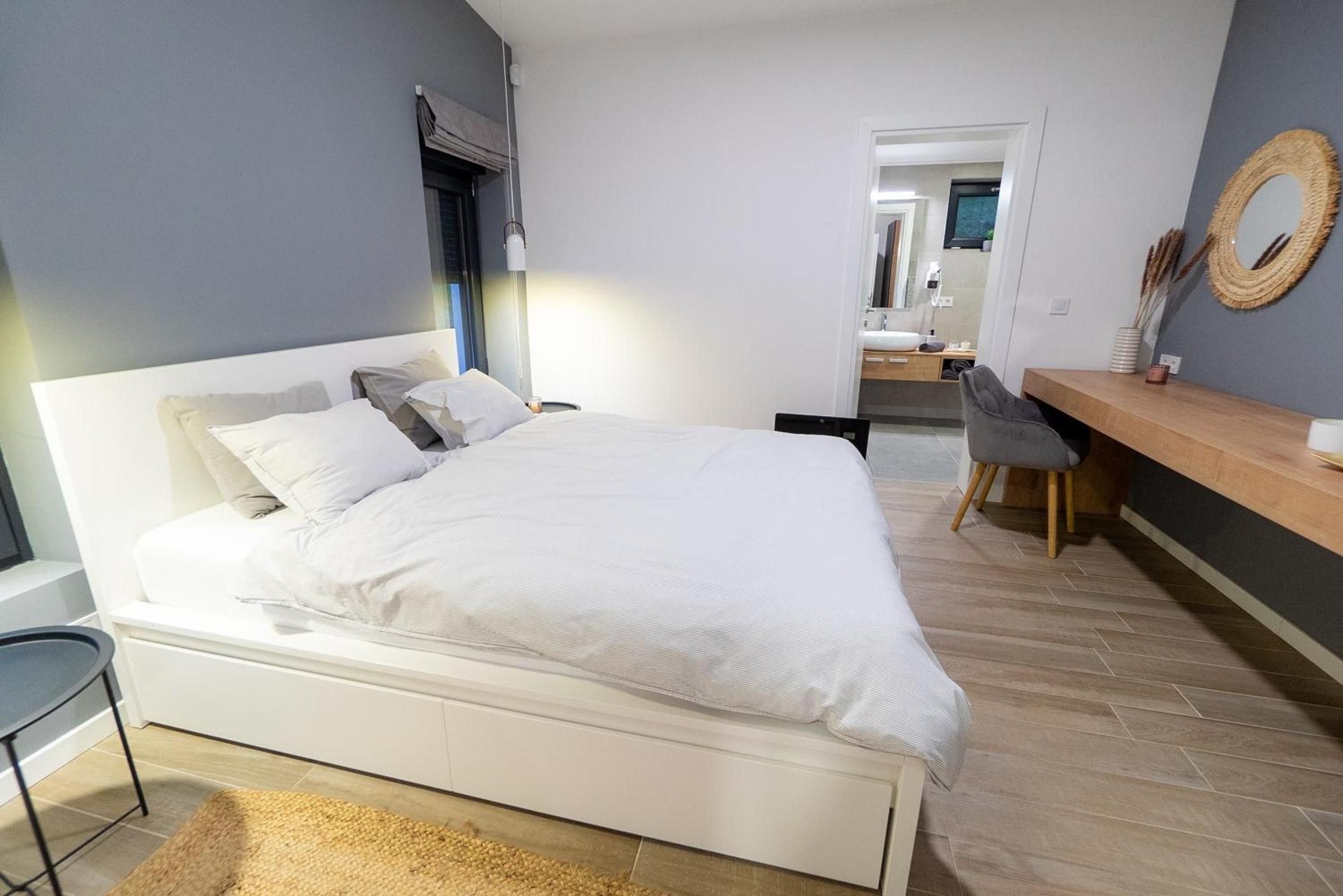 A modern bedroom with a large bed, bedside table, and a chair.