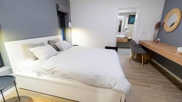 A modern bedroom with a large bed, bedside table, and a chair.