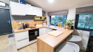 Una cocina moderna con armarios blancos, encimera de madera, horno integrado y ventana con vistas a árboles.