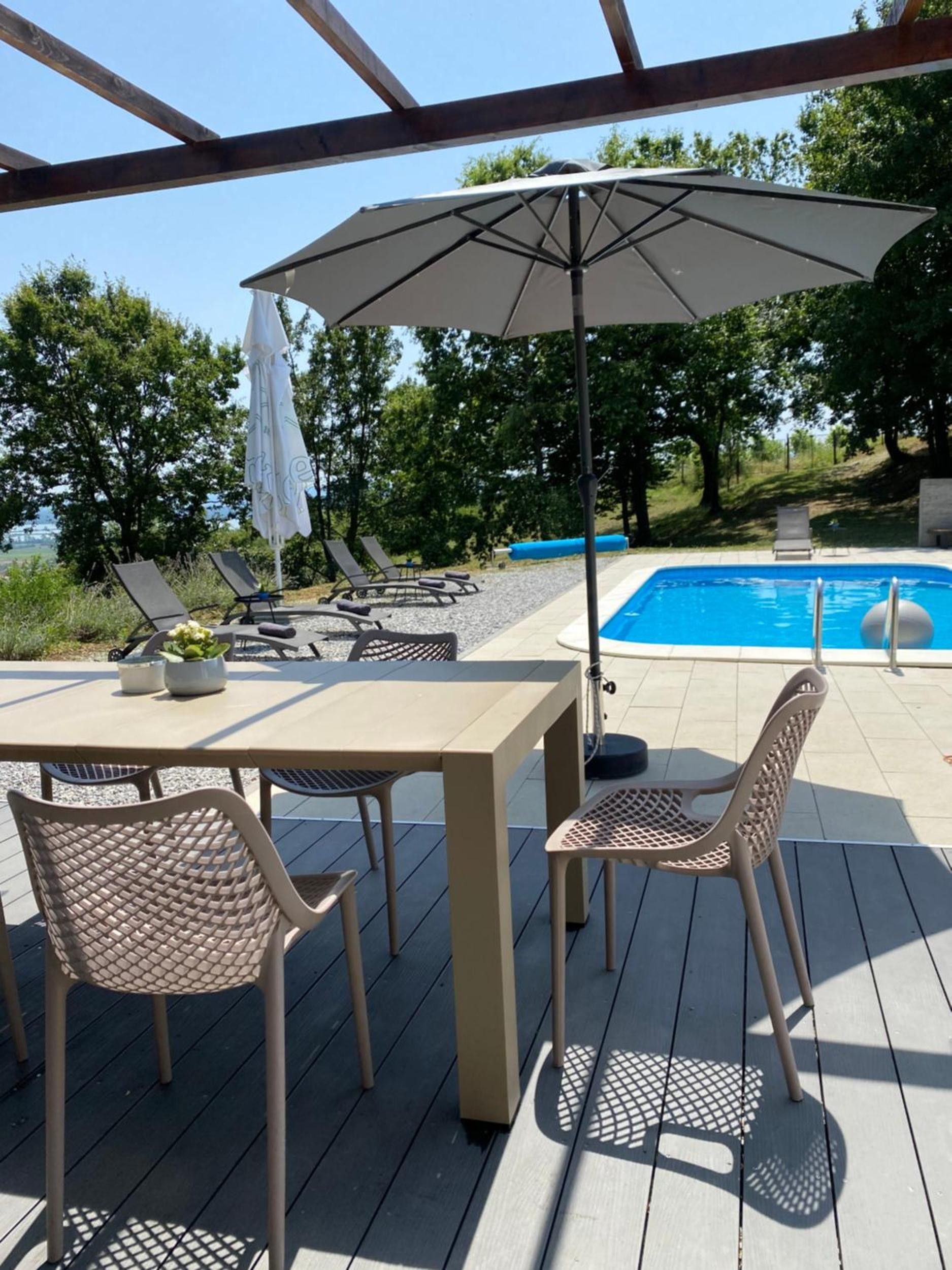 An outdoor deck with a pool, lounge chairs, and a table with chairs.