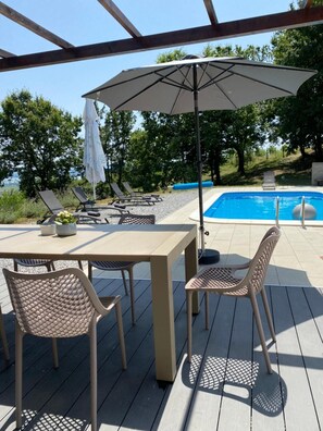 Terraza exterior con piscina, sillas de descanso y una mesa con sillas.