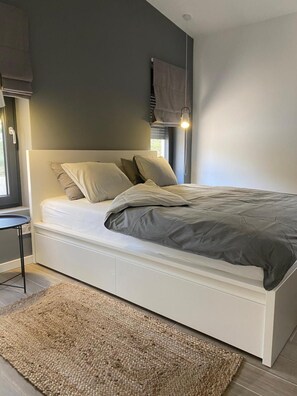 Ein modernes Schlafzimmer mit einem Bett, Nachttischen und einem Fenster mit Vorhängen.