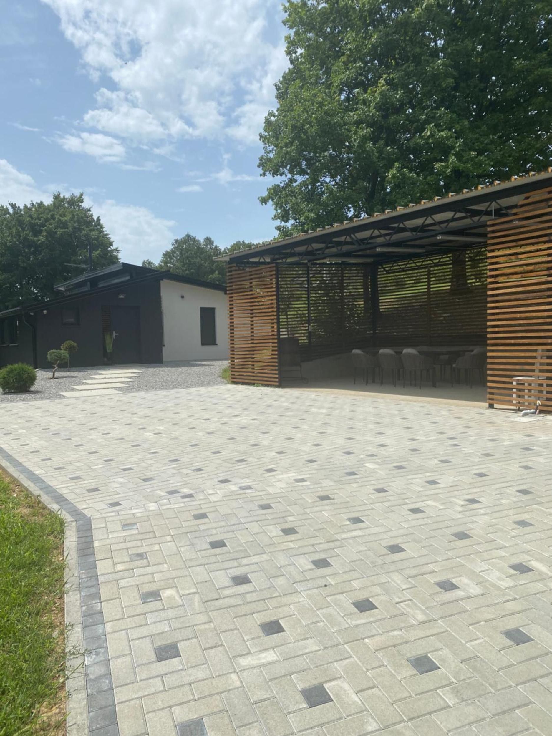 A paved courtyard with a covered seating area and a building with a modern design.