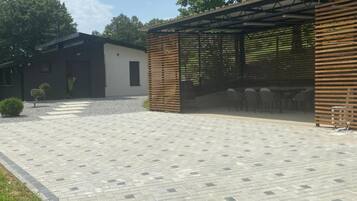 A paved courtyard with a covered seating area and a building with a modern design.