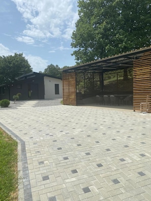 A paved courtyard with a covered seating area and a building with a modern design.