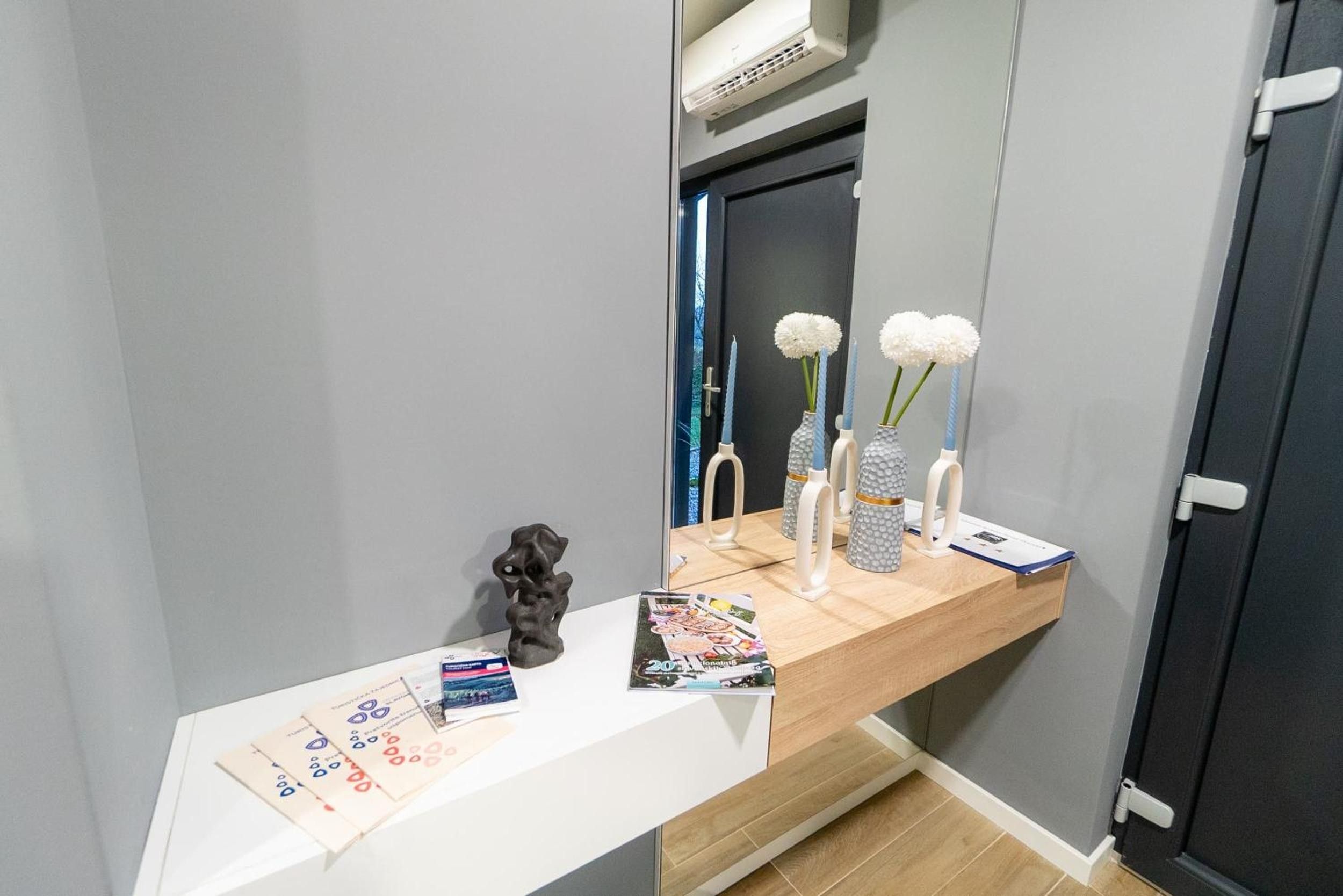 A bathroom vanity with a mirror, a small sculpture, and a magazine on the counter.