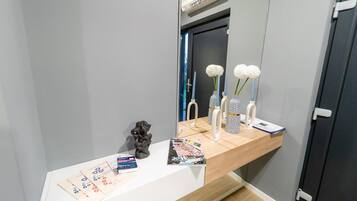 A bathroom vanity with a mirror, a small sculpture, and a magazine on the counter.