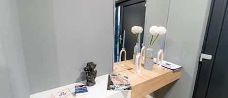 A bathroom vanity with a mirror, a small sculpture, and a magazine on the counter.