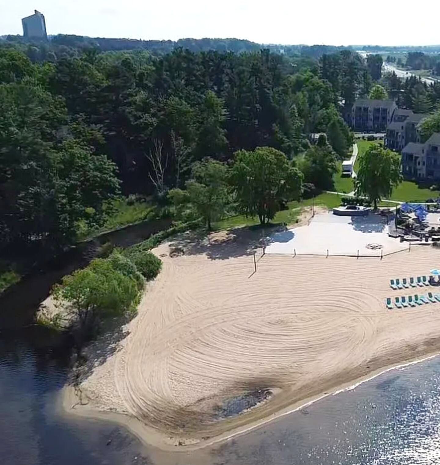 En strand med sandet bredde, et lille bassin og en række liggestole.