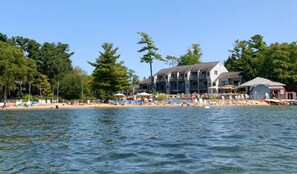 A waterfront hotel with a beach area, including sun loungers and umbrellas.