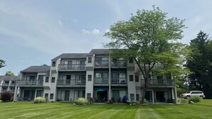 Un edificio residencial de varios pisos con balcones, un césped bien cuidado y un coche estacionado.