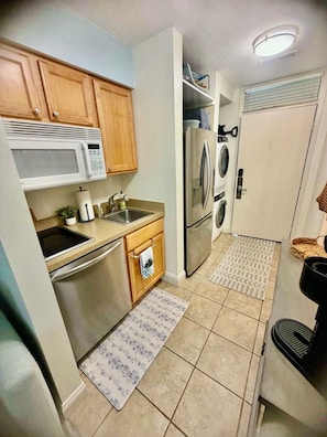 A compact kitchen with a microwave, sink, and stainless steel refrigerator.