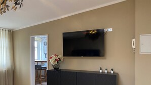A modern living room with a flat-screen TV mounted on the wall, a dark-colored entertainment unit below, and a wooden floor. - Zur Post 1 (Bautzen)