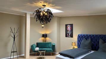 Ein Schlafzimmer mit einem Bett, einem grünen Sofa, einer Stehlampe und einer Deckenleuchte.