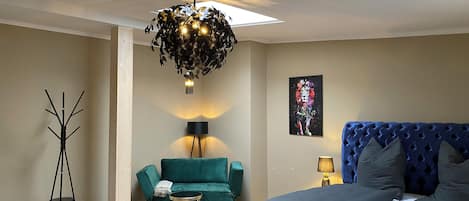 Ein Schlafzimmer mit einem Bett, einem grünen Sofa, einer Stehlampe und einer Deckenleuchte.