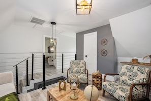 Una sala de estar moderna con una escalera, un sillón estampado, un globo terráqueo y una mesita de madera.