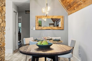 A dining area with a round wooden table, a bowl of apples, and a mirror above. - 3 beds/2.5 bath, A-Frame Palm Tree & Alpaca & Llama Farm (Palm Beach Gardens)