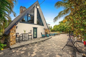 A modern building with a stone facade, large windows, and outdoor seating. - 3 beds/2.5 bath, A-Frame Palm Tree & Alpaca & Llama Farm (Palm Beach Gardens)