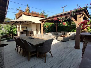 Un patio al aire libre con mesa, sillas y zona de barbacoa.