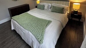 Un dormitori amb un llit, un ventilador de sostre, una làmpada de nit i un mirall fixat a la paret.