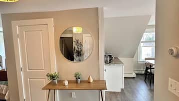 A room with a wooden table, a round mirror, and a door.