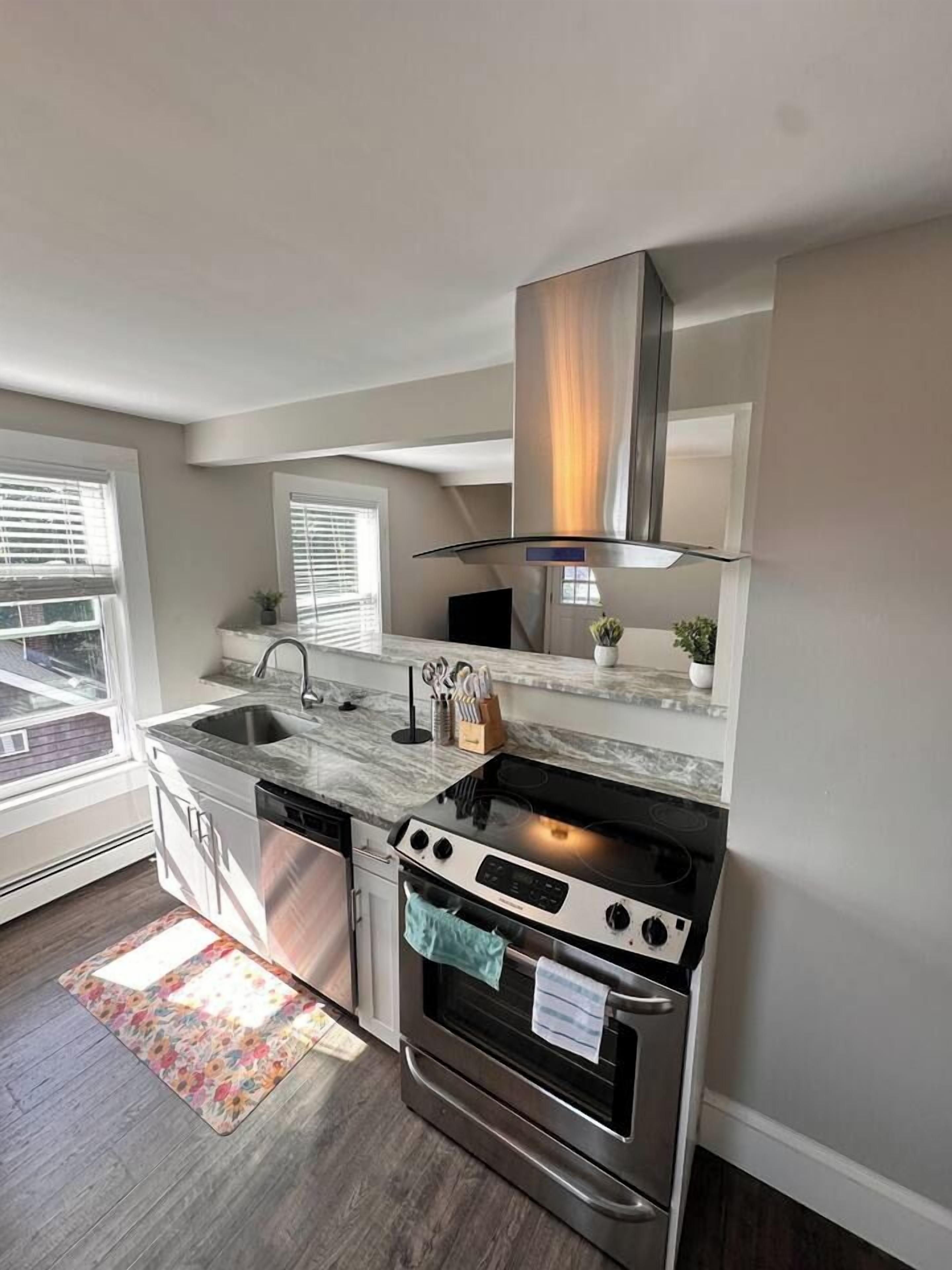 A modern kitchen with a built-in oven, stainless steel sink, and a window overlooking the street.
