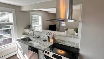 A modern kitchen with a built-in oven, stainless steel sink, and a window overlooking the street.