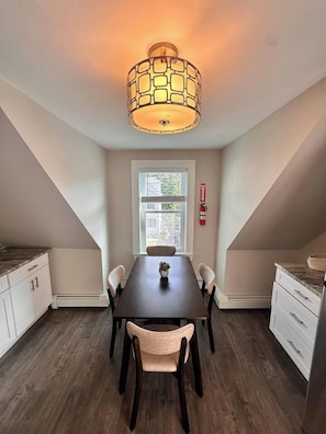 Een eetruimte met een tafel, stoelen, een hanglamp en een raam met uitzicht.