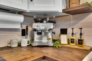 A coffee machine on a wooden countertop with two mugs and two bottles of syrup. - Elk Stargazer | Roll-Out Bed, Hot Tub & Sauna (Benezette)