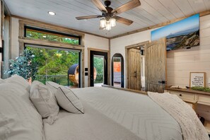 A bedroom with a large bed, a ceiling fan, and a view of the outdoors. - Elk Stargazer | Roll-Out Bed, Hot Tub & Sauna (Benezette)