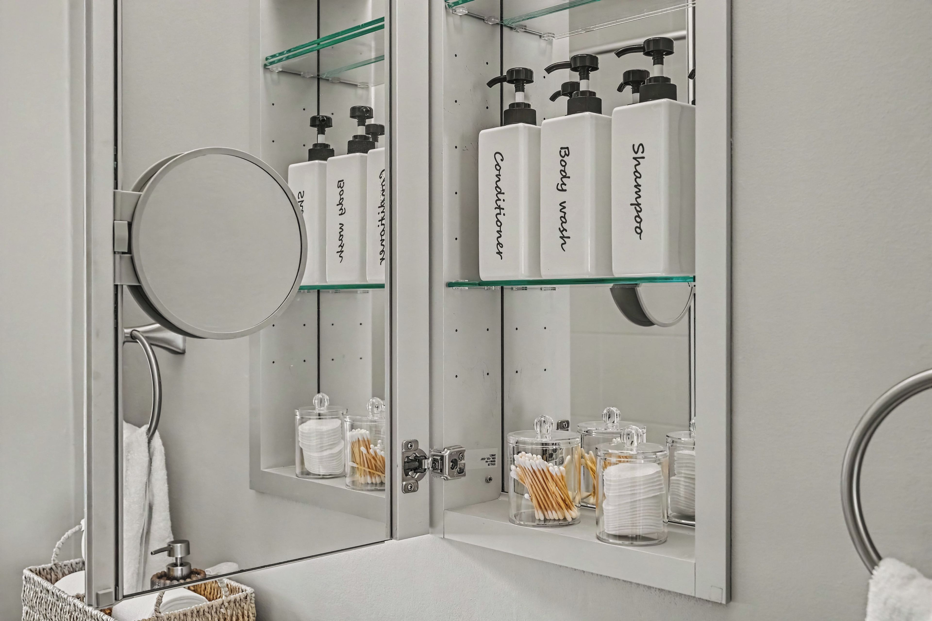 A bathroom with a mirror, a sink, and shelves holding toiletries.