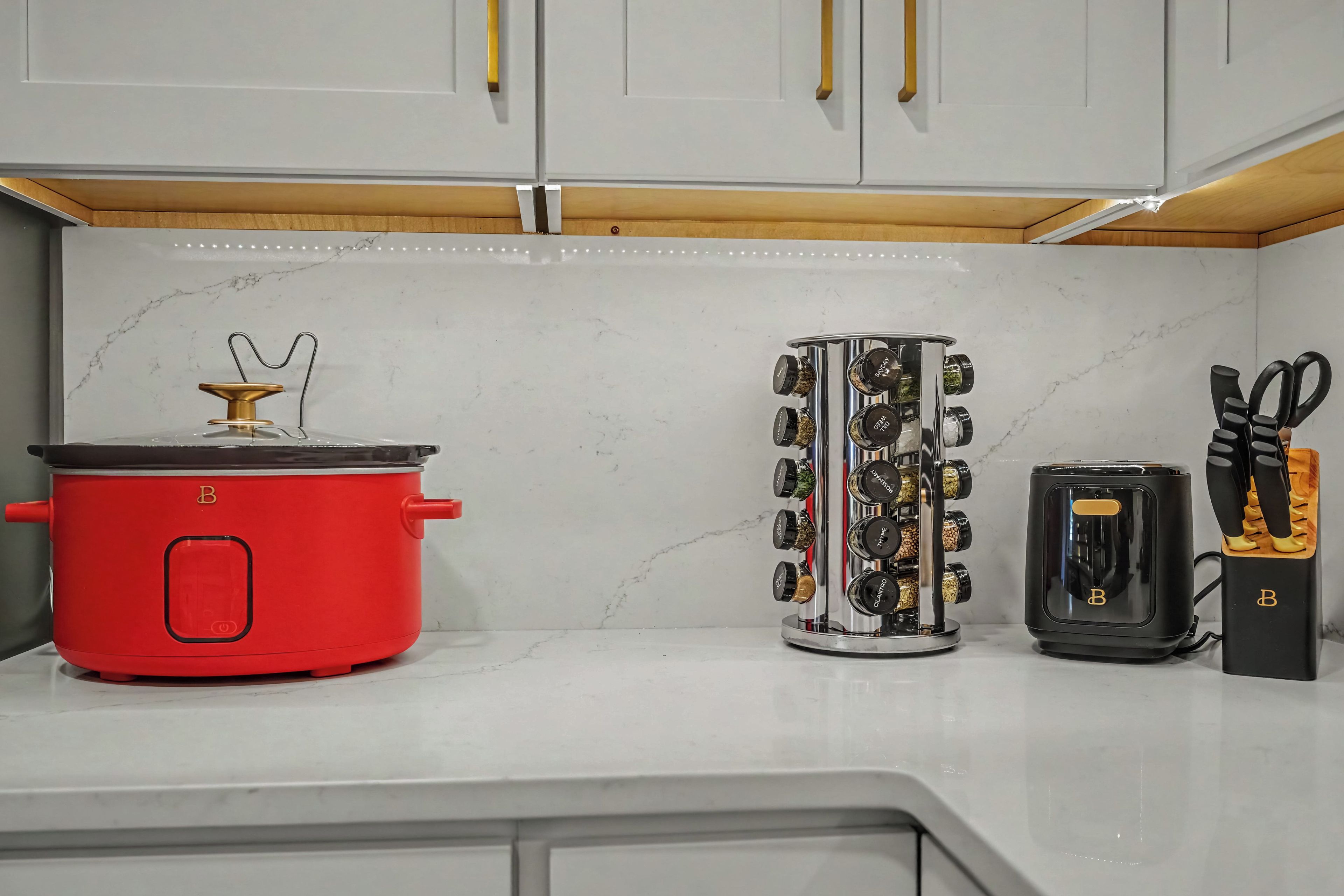 Une cuisine équipée d’une mijoteuse rouge, d’un porte-épices et d’un grille-pain.