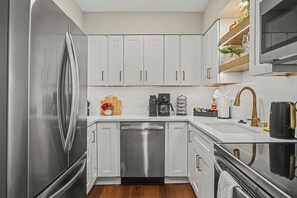 Een moderne keuken met roestvrijstalen apparatuur, witte kastjes en een houten aanrecht.