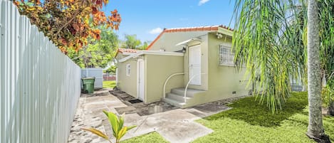 A residential property with a small house, a fenced yard, and a garden area.