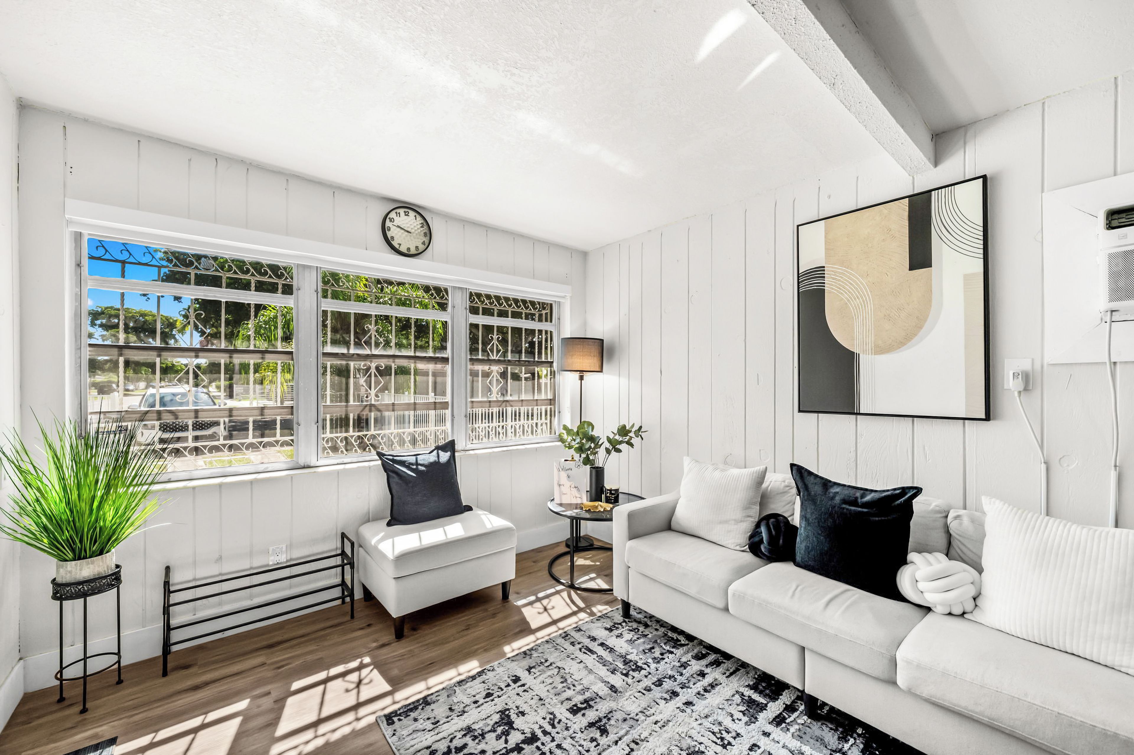 A modern living room with a white sofa, a coffee table, and a large window with decorative metal bars.