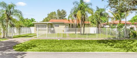 Una zona residencial con casas, una valla blanca y céspedes verdes.