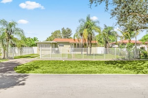 Una zona residencial con casas, una valla blanca y céspedes verdes.