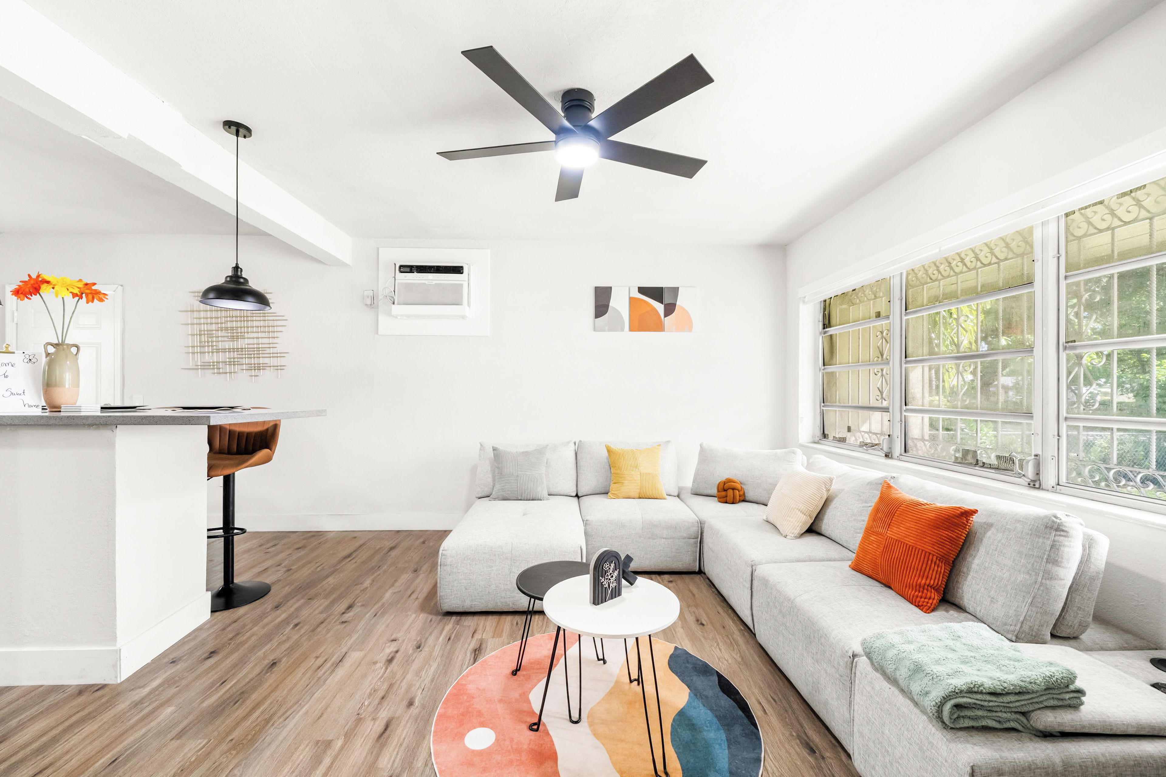 Una sala de estar moderna con un sofá modular, una mesita redonda y un ventilador de techo.