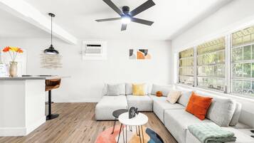 Una sala de estar moderna con un sofá modular, una mesita redonda y un ventilador de techo.
