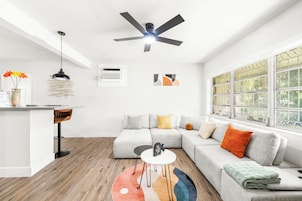A modern living room with a sectional sofa, a small round table, and a ceiling fan.