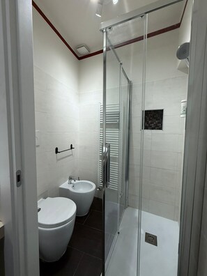 A modern bathroom with a glass-enclosed shower, a bidet, and a toilet. - Rubino | Urban Suite (Valenza)