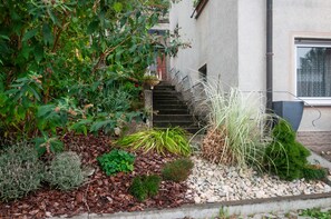 Un jardín con diversas plantas y una escalera de piedra que lleva a un edificio.