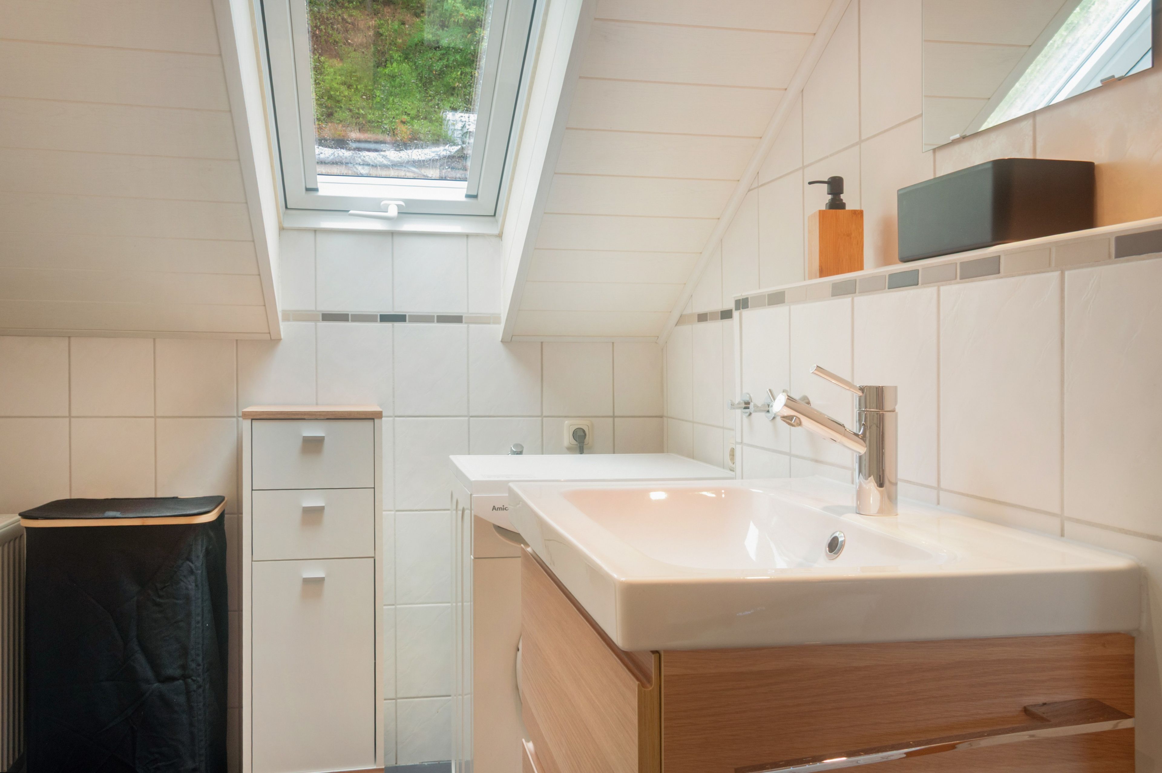 A modern bathroom with a skylight, a sink, and a mirror.