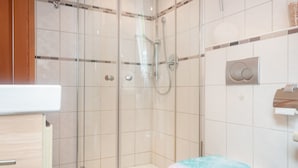 A bathroom with a glass-enclosed shower, a toilet with a colorful seat, and a white sink.